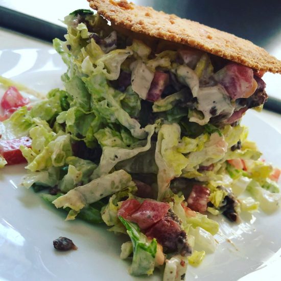 BLT salad with homemade Parmesan cheese crisp on white ceramic plate