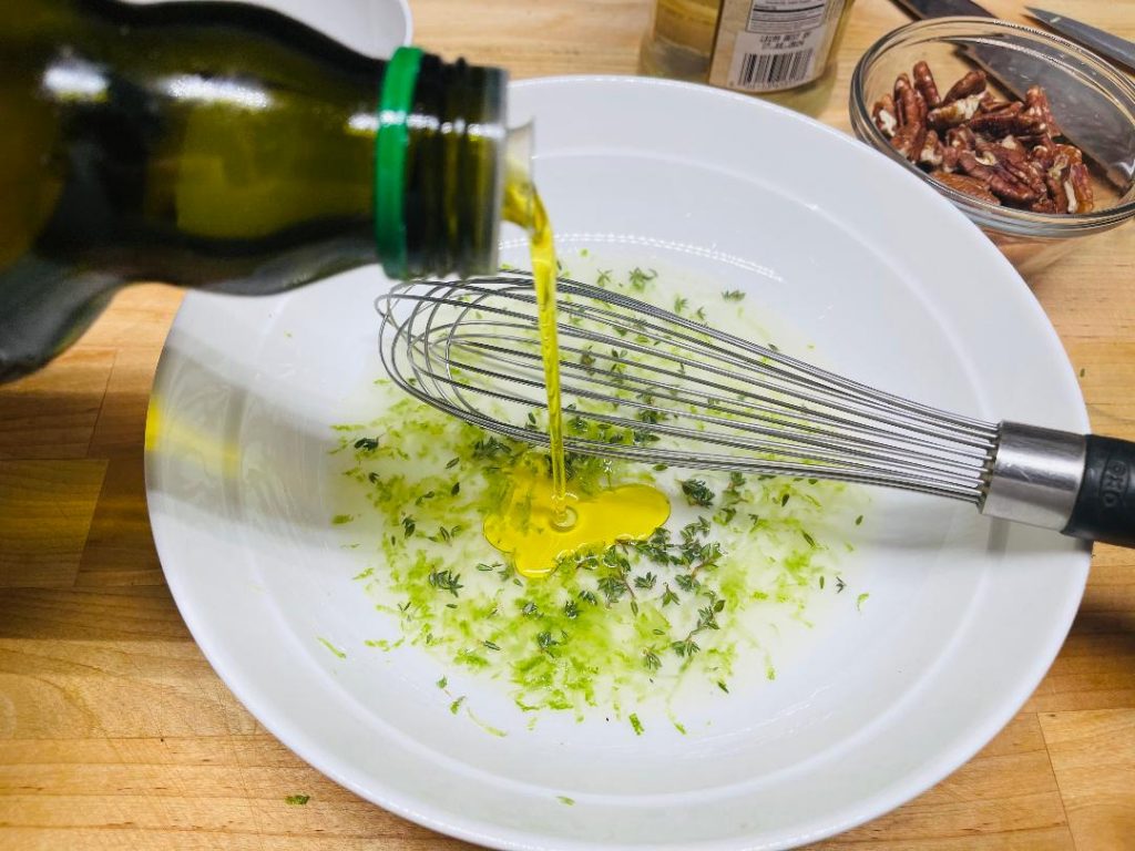 whisking thyme vinaigrette together in a small bowl