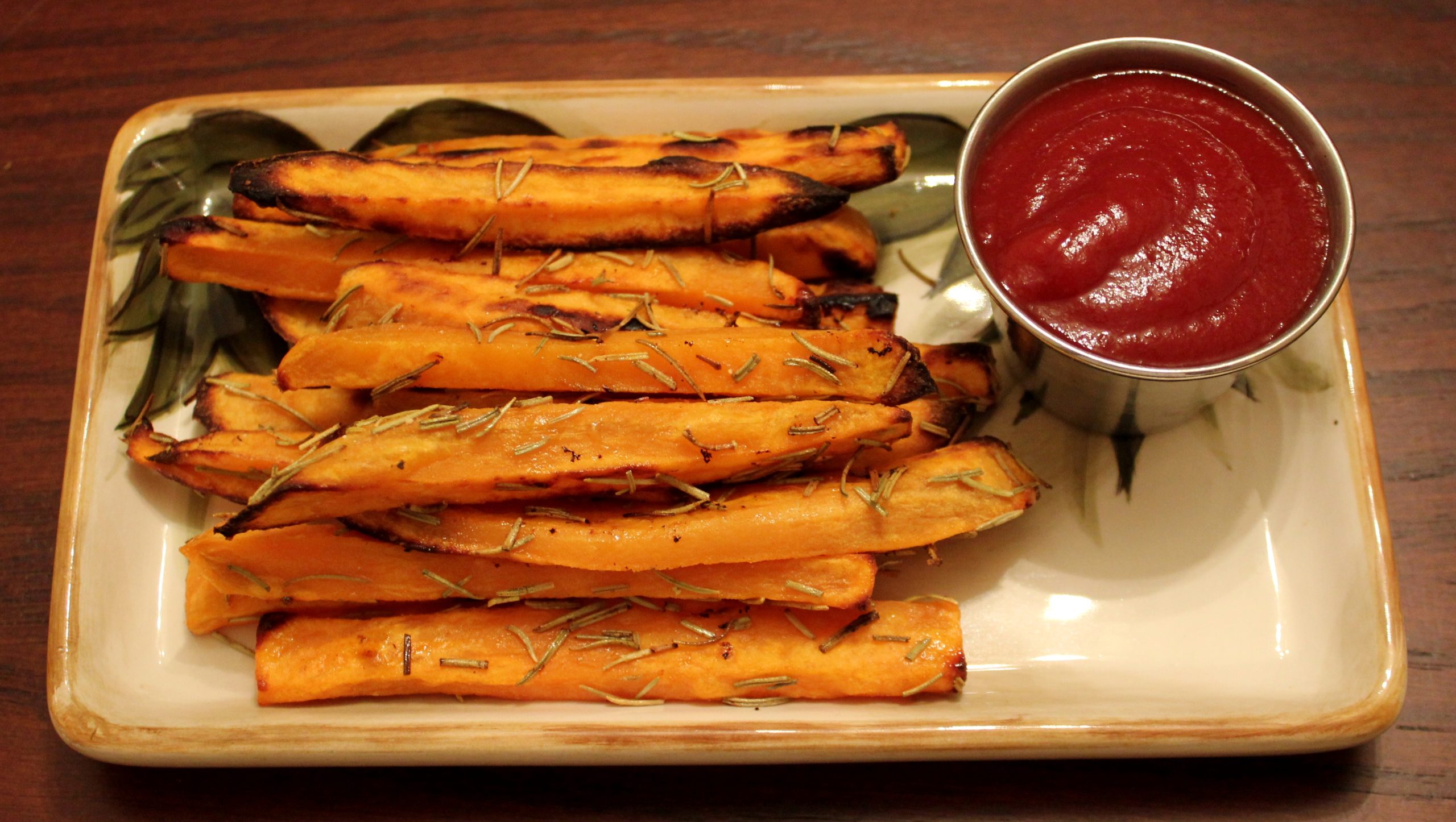 Oven roasted sweet potato fries with rosemary and parmesan on a rustic plate