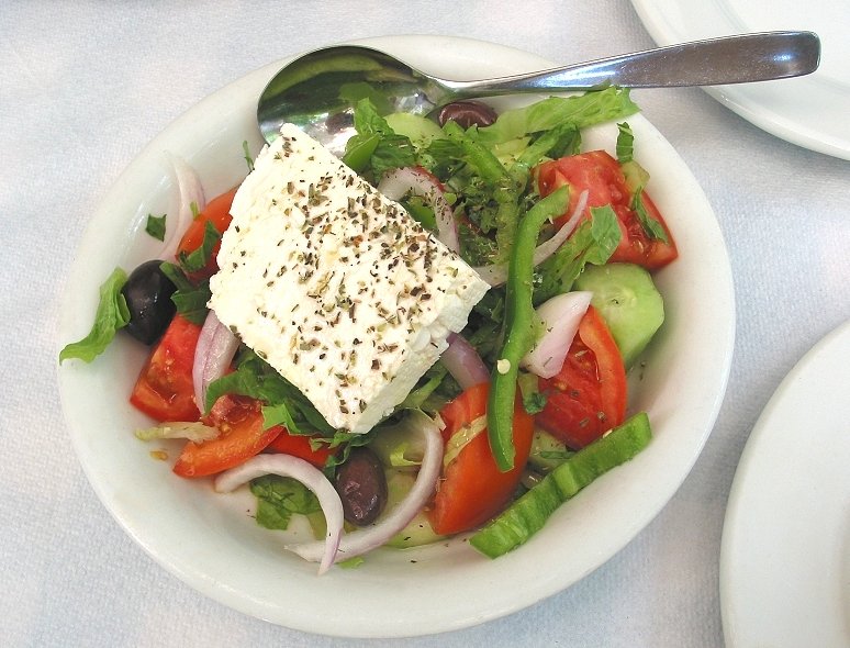 Classic Greek salad horiatiki with chunky tomatoes, cucumber, red onion, olives and feta cheese block